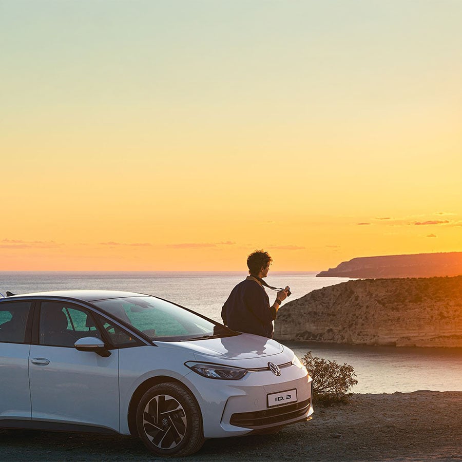 person sat on car watching sunset